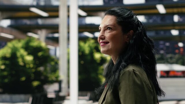 Close-up n upbeat female traveler walking toward the bus station platform during an intercity journey, smiling as she enters the coach terminal to continue a long-distance trip.