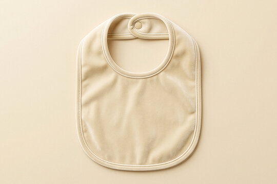 Beige velvet baby bib with snap closure flat on a matching neutral background