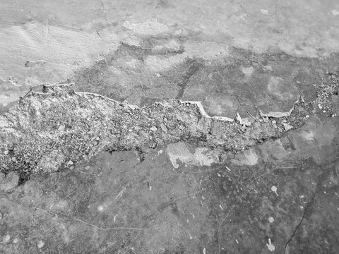 A background texture of a severely cracked and damaged gray concrete surface.