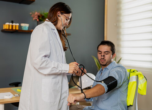 Doctor checking blood pressure of construction worker patient