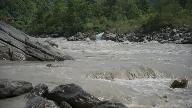 Muddy rapids rushing past massive smooth boulder medium shot