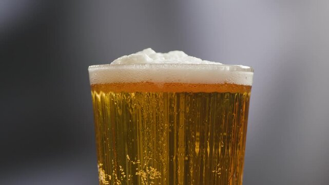 Fresh Spanish small beer served in a small glass with creamy foam at a traditional bar. Classic draft lager, authentic pub atmosphere, close-up food and drink