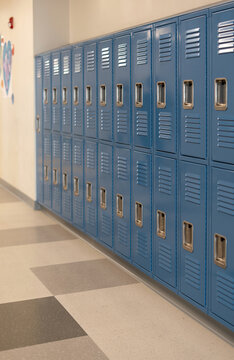 Long row of blue metal school lockers in a school hallway