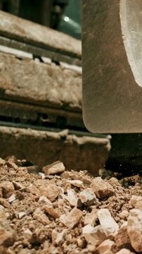 Excavator bucket scooping and dropping heavy gravel and rocks