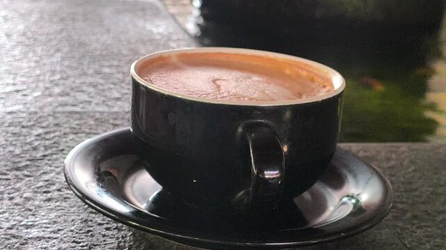 A person enjoying a cup of hot mochaccino topped with creamy foam, creating a cozy and relaxing caf&eacute; moment with rich coffee and chocolate flavors, perfect for lifestyle photography.