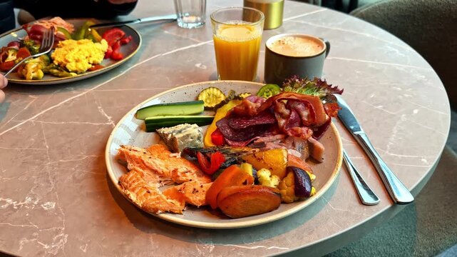 Camera zooms in cloze up on hearty breakfast plate featuring smoked salmon cured meats cheese and roasted vegetables in Flam Aurland Norway
