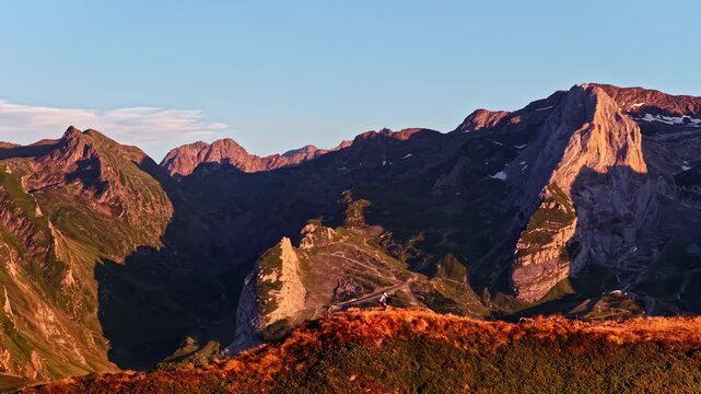 Hiker admiring the sunset from a mountaintop at Col d'Aubisque in the Pyrenees, France