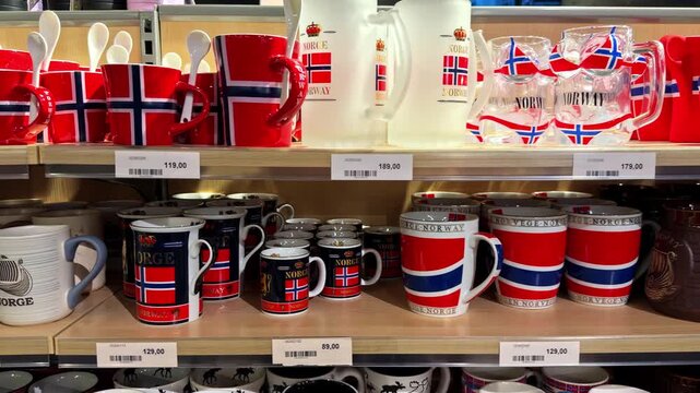 Shelves display colorful Norway souvenir mugs and glassware with national flag designs