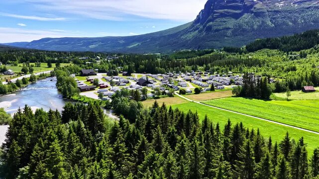 Beautiful aerial footage of a Norwegian valley with a large RV park beside a river and forest