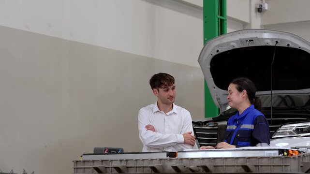 Mechanic service garage car hood technician woman man discuss vehicle inspection maintenance auto repair workshop staff with customer under open hood