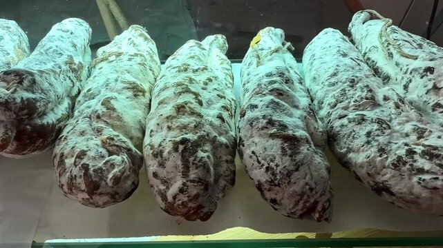 Row of traditional cured saucisson sausages with white mold rind hangs on display near Col d'Aubisque France