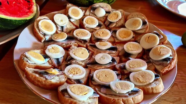 Open-faced sandwiches topped with sprats and sliced boiled eggs on serving platter