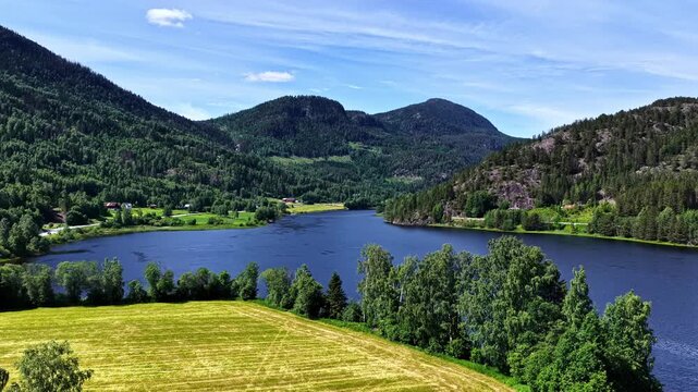 A Peaceful Lake Framed by Forested Mountains and Golden Fields Along a Quiet Road From Fl&aring;m to Oslo, Norway - Aerial Drone Shot
