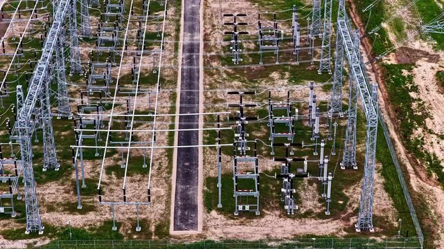 Top down aerial flyover of electrical substation showing rows of switchgear, circuit breakers and transmission structures
