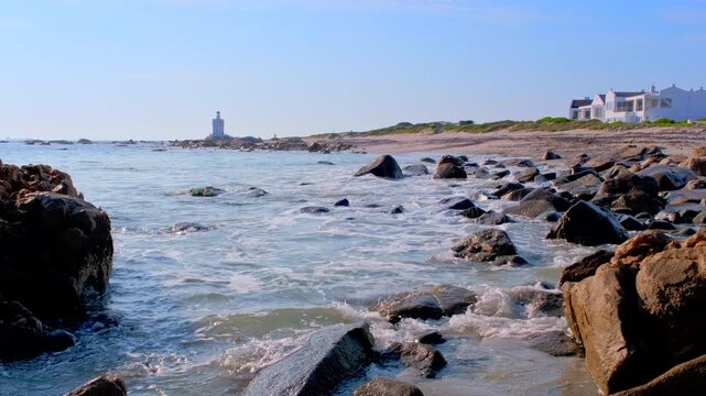 Waves crash into Shelley Point coastline with Stompneuspunt Lighthouse in back