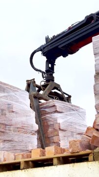 Vertical. Brick grab of loader crane used to move pallet of bricks from truck