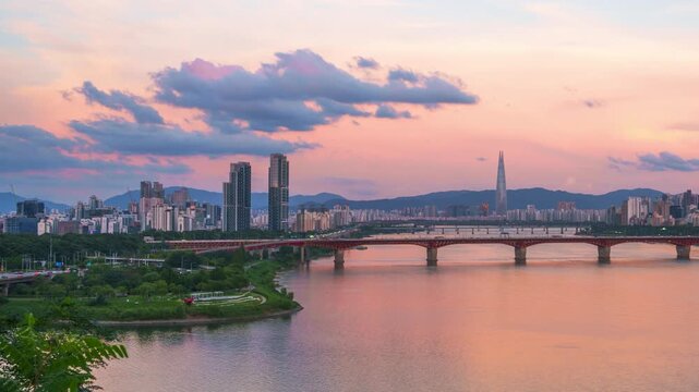 Pink summer sunset glows over Han river as Seongsu bridge and Lotte tower rise against Seoul skyline and mountains