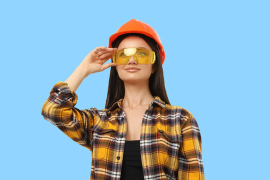 A woman in safety gear poses against a blue background