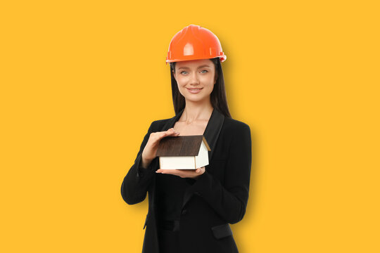 Woman shows model house while wearing protective headgear
