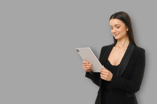 Young woman stands in office space while using a tablet