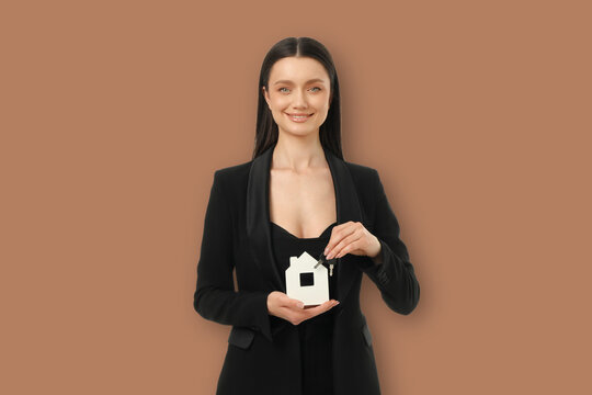 Young worker smiles while holding house model and key