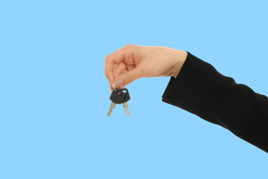 A hand presents keys against a blue backdrop