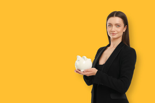 Young woman stands with a piggy bank in a yellow space
