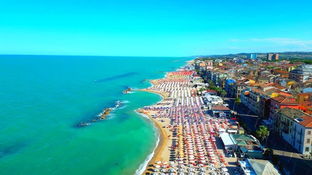 Inspiring aerial push-in shot from Porto Recanati, a high-rise capture featuring the aquamarine Adriatic Sea on the left, sandy beach with parasols and loungers in the centre, buildings on the right