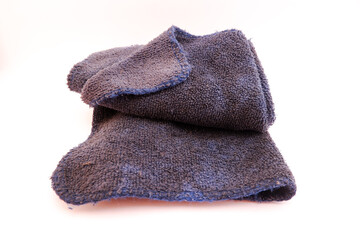 Fototapeta premium Dark blue microfiber cleaning cloth showing visible dirt and signs of wear after prolonged use. The fabric appears stained and slightly frayed along the edges, highlighting frequent use in household