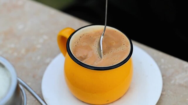 Spoon stirring jaggery gur sweetener inside cup of hot Pakistani chai milk tea 180fps Captured in Cinematic High Detail Footage