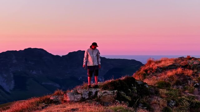 Aerial parallax circles hiker standing on rocky ridge above Col d'Aubisque during vivid Pyrenees sunset
