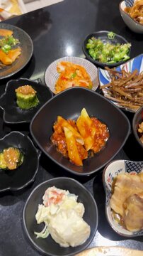 Hand Placing Egg Yolk Over Japanese Side Dishes in Bangkok Izakaya