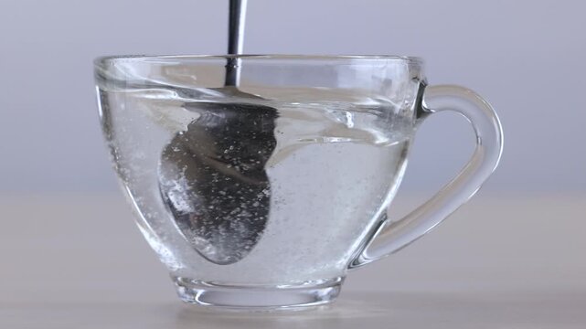 Stirring Sugar Crystals into Hot Water in a Glass Mug