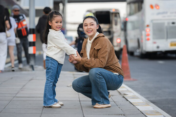Fototapeta premium happy mother holding hand her daughter on city street