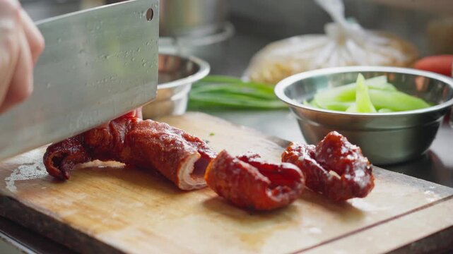 Close up view of marinated sausages being cut with a kitchen knife on the kitchen cutting board