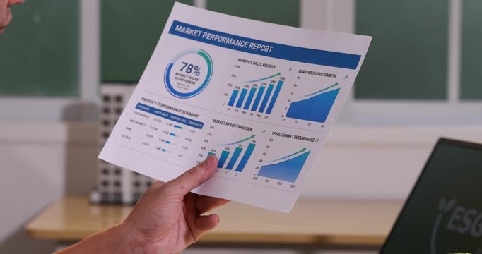Hand holding a market performance report with charts and growth graphs in an office, business analytics, finance results, and planning data.