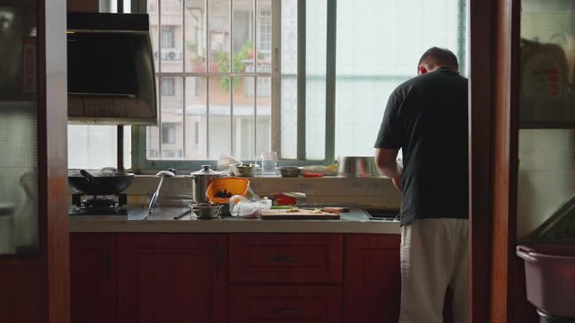 Man preparing ingredients in home kitchen with back to camera