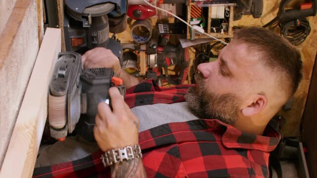 Vertical video. Carpenter occupation. Joinery process. Man smoothing board surface with belt sander in workshop interior with tools kit on shelves.