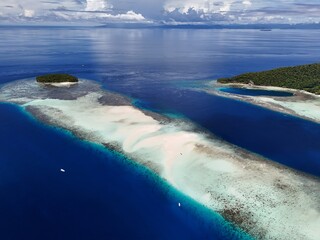 Aerial drone footage of a beautiful sandbar surrounded by crystal-clear turquoise water in Raja Ampat, Indonesia. The tropical seascape showcases pristine white sand, shallow waters, and the natural b © Andri Pradana