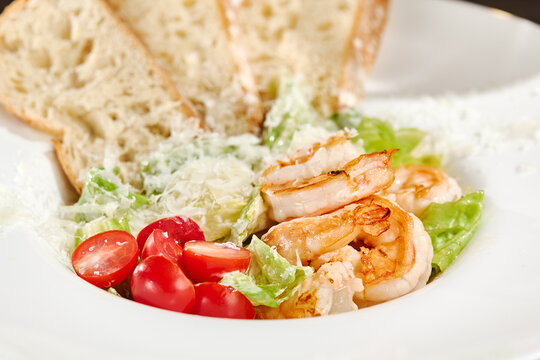 Grilled shrimp Caesar salad with glossy prawns, ripe tomatoes, creamy dressing and parmesan captured in close-up detail