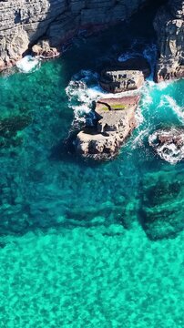 Aerial View of Turquoise Ocean Waves Crashing Against Coastal Rocks