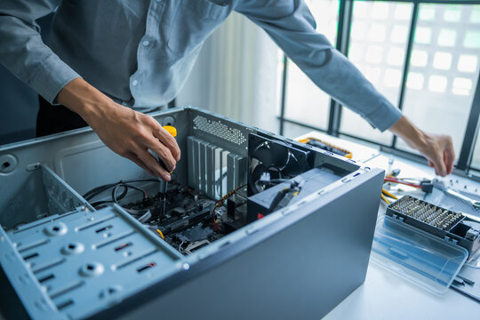 Asian IT engineer man fixing mainboard in pc case on working table