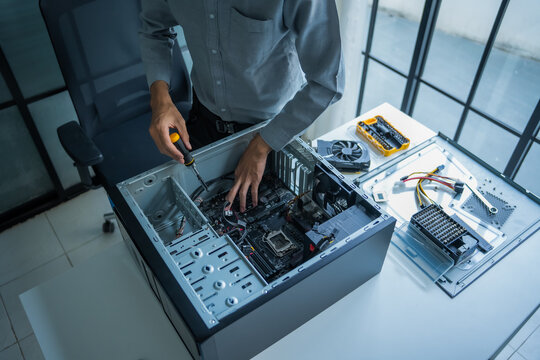 Asian IT engineer man fixing mainboard in pc case on working table