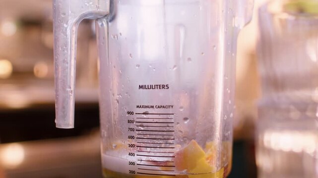 Beverage making. Drink mixing. Bartender pouring liquid in blender measuring scale pitcher with fruit pieces. Sweet cocktail ingredient.