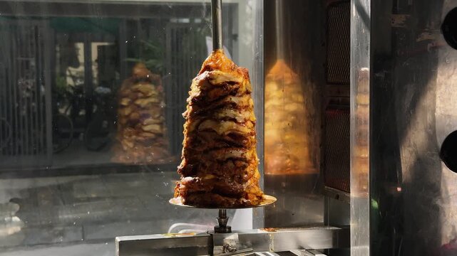 Close Up of Doner Kebab Meat Cone rotating on Rotisserie Spit in Street Restaurant