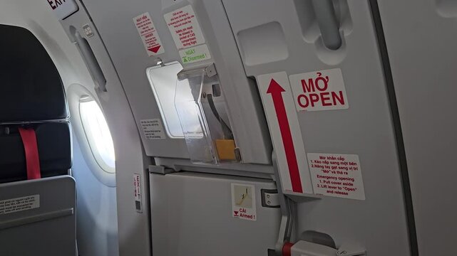 Airplane emergency exit door handle and safety instruction signs in Vietnamese and English.
