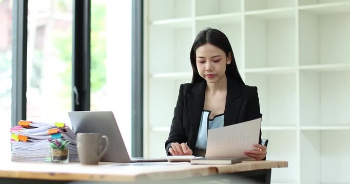 Young businesswoman analyzing financial documents and data, managing budget planning in a modern office
