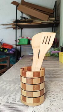Person Arranging Bamboo Kitchen Utensils into Handcrafted Holder