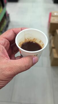 A hand holding a coffee cup while shopping in a modern supermarket