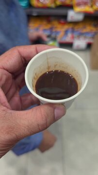 A hand holding a coffee cup while shopping in a modern supermarket